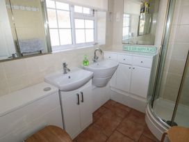 A bathroom with two sinks a corner shower cabinet white cabinets and a window at Kites - 52 Gower Holiday Village in Scurlage near Port Eynon and Rhossili