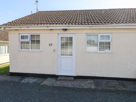 Front view of a single-story building with two windows and a door in the center at Kites - 52 Gower Holiday Village in Scurlage near Port Eynon and Rhossili