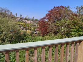 A wooden balcony railing overlooking trees and terraced garden at The Beach House in Watermouth near Combe Martin