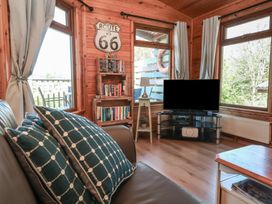 A living room with a sofa pillows bookshelf and television at The Beach House in Watermouth near Combe Martin