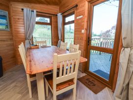 A dining area with a wooden table and six chairs next to windows and a glass door leading to a deck at The Beach House in Watermouth near Combe Martin