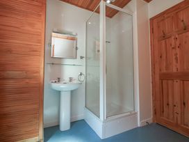 A bathroom with a pedestal sink a mirrored cabinet a glass shower enclosure and wooden doors at The Beach House in Watermouth near Combe Martin