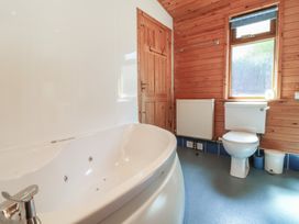 A bathroom with a white bathtub toilet wooden door window and radiator at The Beach House in Watermouth near Combe Martin
