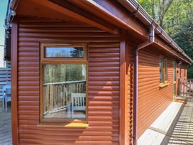 Exterior view of a wooden cabin with windows and a deck surrounded by trees at The Beach House in Watermouth near Combe Martin
