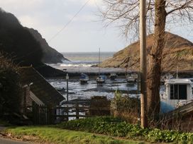 A coastal scene with boats on mudflats between hills and a tree in the foreground at The Beach House in Watermouth near Combe Martin