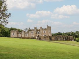A large castle with towers and battlements on a grassy slope under a blue sky