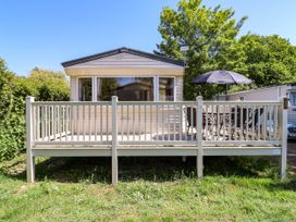 A caravan with a wooden deck patio and outdoor dining set with umbrella at Caravan 941 in Clacton-On-Sea