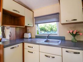A kitchen with a sink and faucet a toaster and flowers in a vase on the counter at Caravan 941 in Clacton-On-Sea