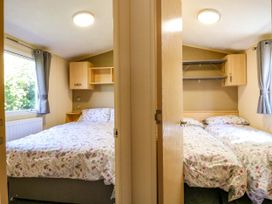 Two bedrooms with floral bedcovers separated by a wall each with window and wooden shelves Caravan 941 Clacton-On-Sea