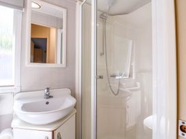 A bathroom with a sink and mirror next to a shower stall at Caravan 941 in Clacton-On-Sea