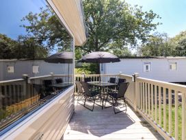 An outdoor deck with a table six chairs and an umbrella next to a white caravan at Caravan 941 in Clacton-On-Sea