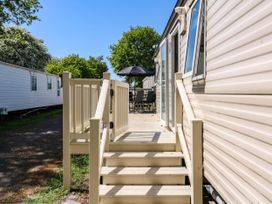 A staircase leading to a deck with outdoor table and umbrella next to a caravan at Caravan 941 in Clacton-On-Sea