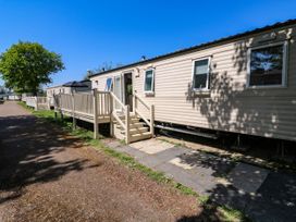 A row of caravans with wooden veranda and steps along a dirt path under a blue sky at Caravan 941 in Clacton-On-Sea