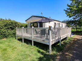 A caravan with a fenced deck and outdoor umbrella in a grassy area at Caravan 941 in Clacton-On-Sea