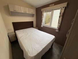A bedroom with a bed, wardrobe and a window at Caravan 941 Clacton-On-Sea