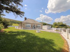 A detached bungalow house with a front garden and driveway under a blue sky at Killelton Cottage in Camp County Kerry