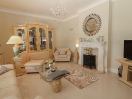 A living room with a glass coffee table a beige sofa a cabinet and a fireplace at Killelton Cottage Camp County Kerry