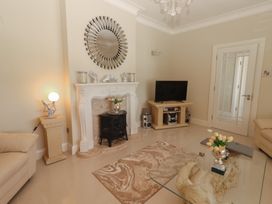 A living room with a glass coffee table with flowers on it a decorative fireplace a television on a stand and beige sofas at Killelton Cottage in Camp County Kerry