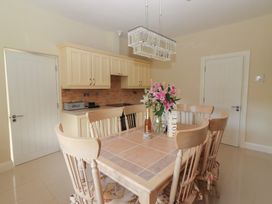 A kitchen with a tiled dining table, six wooden chairs, and a bouquet of flowers on the table in Killelton Cottage Camp County Kerry