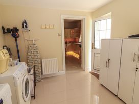 A utility room with a washing machine ironing board cabinets and a doorway leading to a kitchen at Killelton Cottage in Camp County Kerry