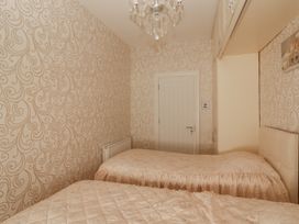 A bedroom with two single beds and cream patterned wallpaper at Killelton Cottage in Camp County Kerry