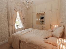 A bedroom with a bed and built-in wardrobes with a mirror and flowers near a window at Killelton Cottage in Camp County Kerry