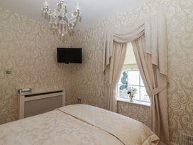 A bedroom with patterned wallpaper a mounted television ornate curtains and a bed at Killelton Cottage Camp County Kerry