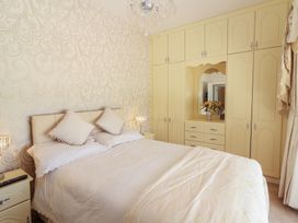 A bedroom with a double bed two pillows bedside tables lamps a built in wardrobe with a mirror and flowers at Killelton Cottage in Camp County Kerry