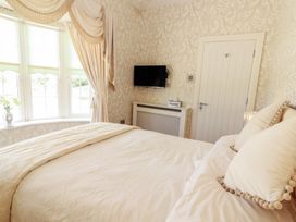 A bedroom with a bed and pillows near a window with drapes and a wall-mounted television at Killelton Cottage in Camp County Kerry