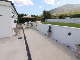 An outdoor patio area with stone tables and benches umbrellas and potted plants at Killelton Cottage in Camp County Kerry