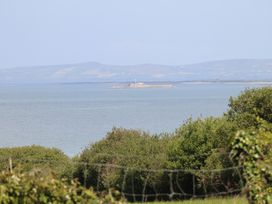 A coastal view with water and an island featuring a white lighthouse with hills in the background at Killelton Cottage in Camp County Kerry