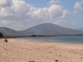 A sandy beach with water and mountains in the background under a partly cloudy sky