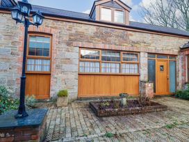 An outdoor area with a stone wall and wooden doors at The Coach House in Falmouth