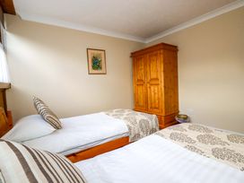 A bedroom with two beds and a wooden wardrobe at The Coach House in Falmouth