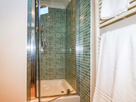 A shower enclosure with tiled walls and towels at The Coach House in Falmouth