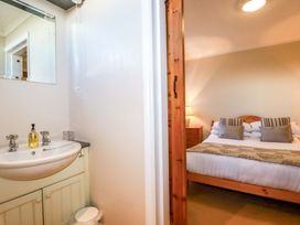 A bathroom with a sink and mirror connected to a bedroom at The Coach House in Falmouth