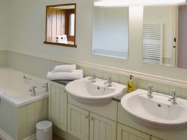 A bathroom with two wash basins and a bath tub at The Coach House Budock Water near Falmouth
