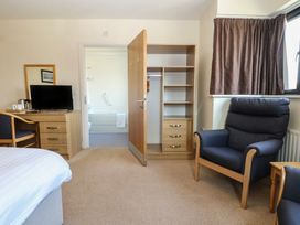 A bedroom with a bed, chair, table, television and wardrobe at Bedroom 10 in Littlehampton