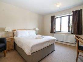 A bedroom with a bed, nightstand, and chair at Bedroom 9 in Littlehampton