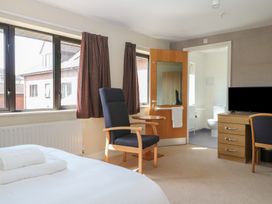 A bedroom with a bed, armchair and TV at Sunset Quarters at Marine Court, Littlehampton