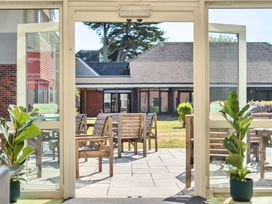 An outdoor area with chairs and tables visible through a glass door at Marine Court First-floor Double Bedroom with Wet Room Littlehampton