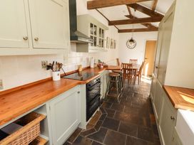 A kitchen with cabinets and a table with chairs at 3 Christon Bank Mews Christon Bank