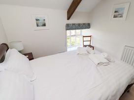 A bedroom with a bed and a chair at 3 Christon Bank Mews in Christon Bank