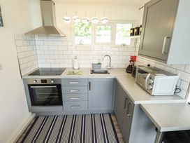 A kitchen with grey cabinets a stove microwave paper towel holder and a striped rug at 99 Cherry Park in Chapel St Leonards