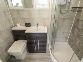 A bathroom with a toilet, a sink with a cabinet, and a shower cubicle at 99 Cherry Park in Chapel St Leonards