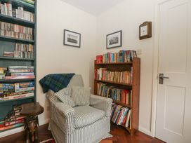 A reading room with books on shelves and an armchair at St. Marys House Church Westcote near Bledington