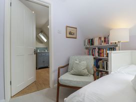 A bedroom with a chair and a doorway to a bathroom at St. Marys House Church Westcote near Bledington