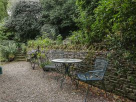 A garden with a table and chairs near a stone wall at St. Marys House Church Westcote near Bledington