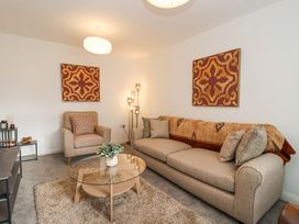A living room with a beige sofa and armchair a glass coffee table a floor lamp and wall art at Peninsula Cottages - The Tors in Tavistock