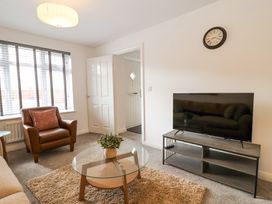 A living room with a glass coffee table and a television on a stand at Peninsula Cottages - The Tors in Tavistock